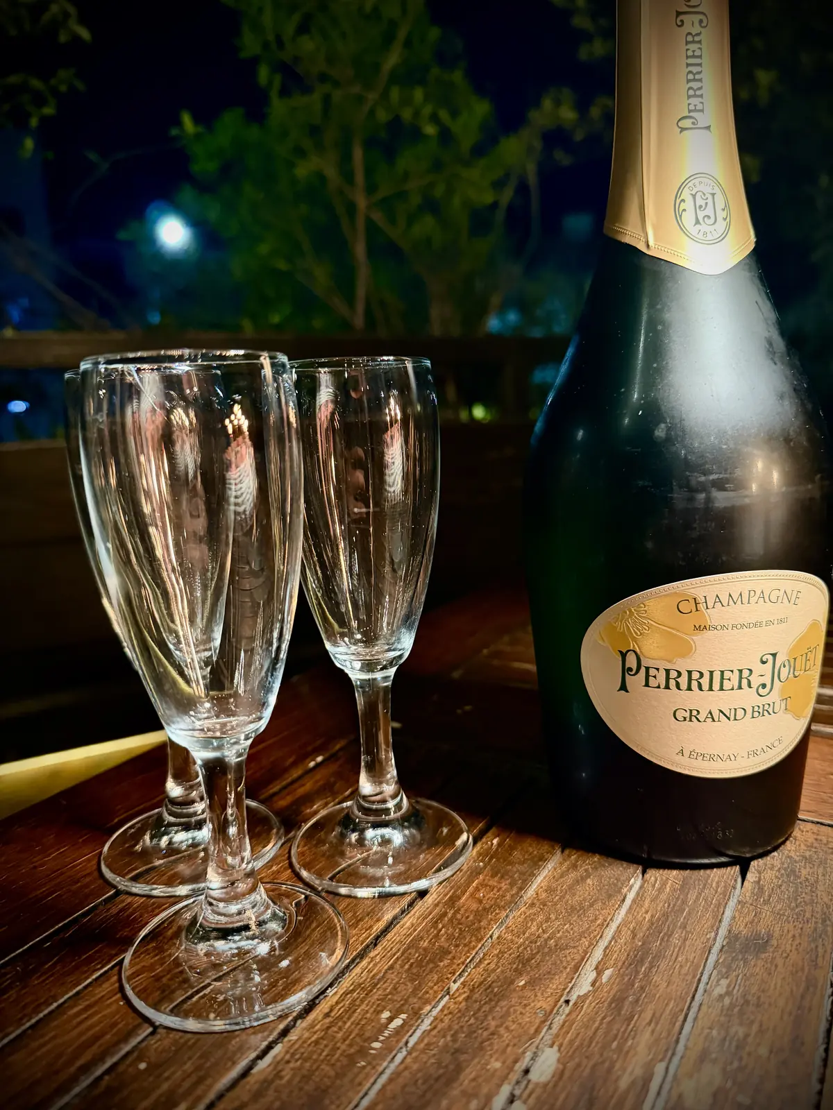 Una bottiglia di champagne e due flûte sul tavolo in legno della Terrazza