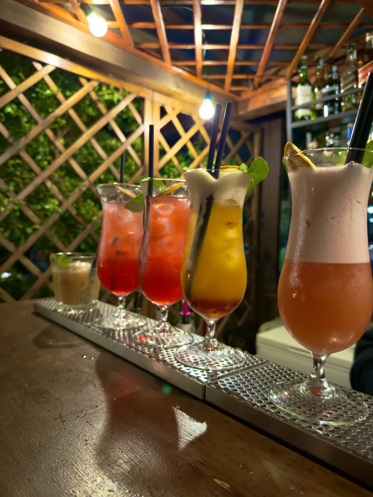 Cinque cocktail colorati in fila sul bancone di Botanico