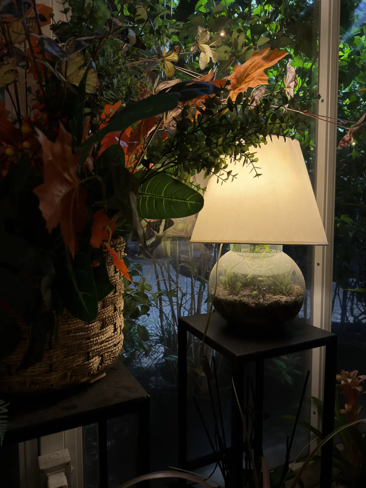 Una lampada accesa tra piante e fiori nella serra di Botanico