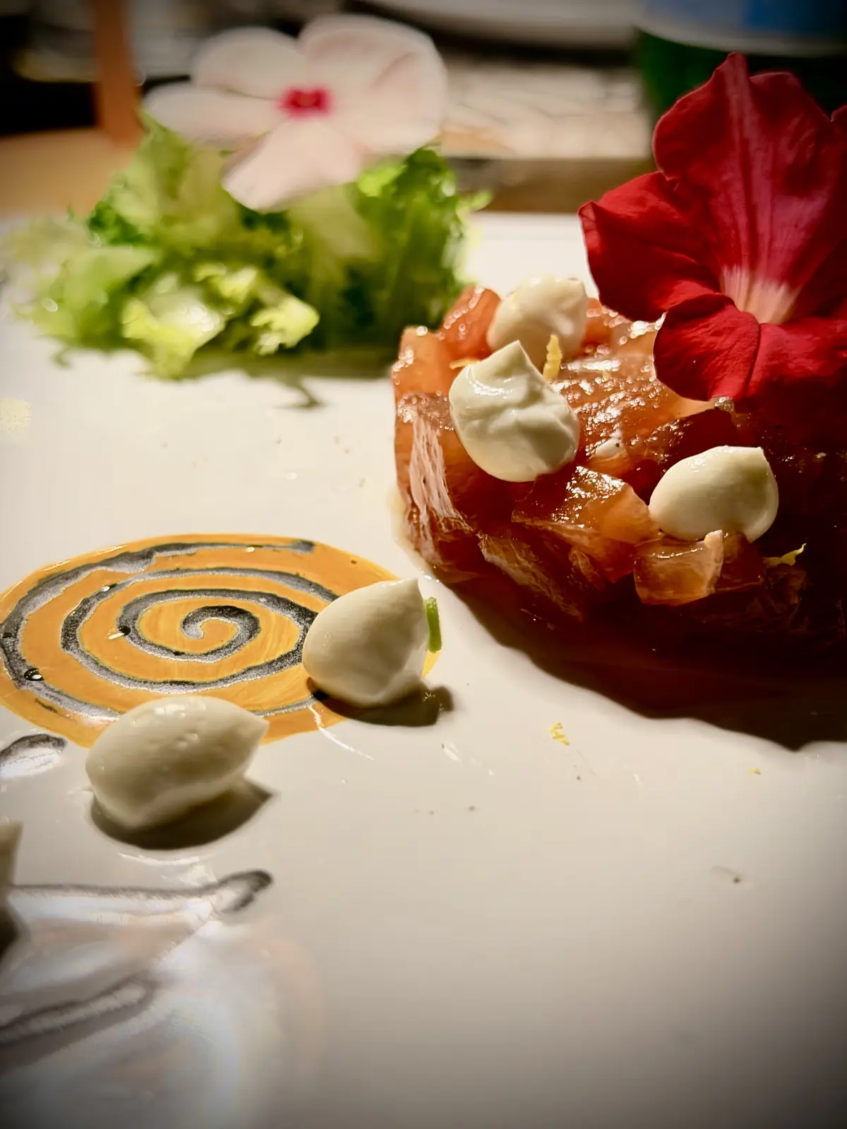 Una tartare con fiori e mozzarelline, servita sul piatto con la spirale di Botanico