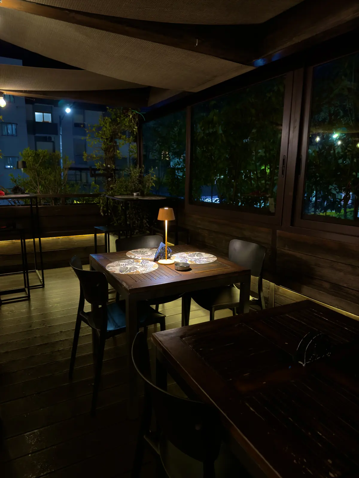 Un tavolo apparecchiato sulla Terrazza Botanico di sera, con la città sullo sfondo